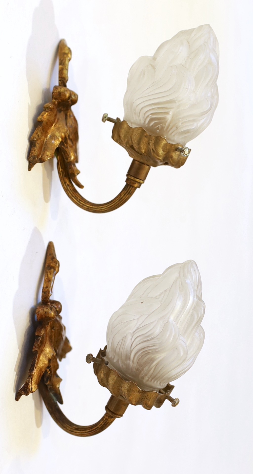 A pair of 1920s brass wall lights with frosted flame glass shades and a pair of brass ribbon back wall lights with lustre shades, height 14cm & height 12cm